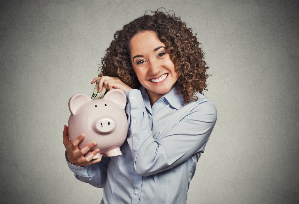 Woman Putting Money In Piggy Bank Smiling Retirement Saving.jpg